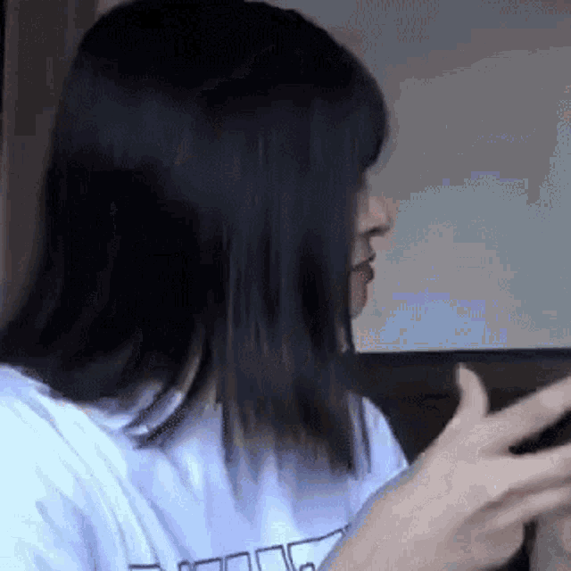 a woman with long black hair is wearing a white t-shirt with a graphic on it .