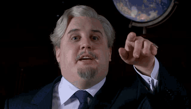 a man in a suit and tie points at something