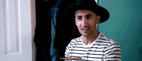 a man wearing a hat and a striped shirt is sitting in a room .