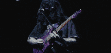 a man playing drums in a dark room with smoke coming out of the drum set