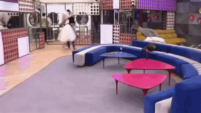 a woman in a white dress is dancing in a laundromat with a couch and tables