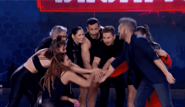 a group of people putting their hands together in front of a sign that says ' a '