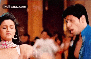 a man and a woman are dancing in a room with a crowd of people .