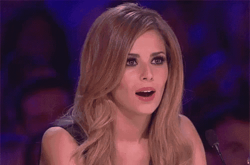 a woman is sitting in front of a microphone with her mouth open and a surprised look on her face .
