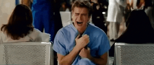a man in a scrub top is crying while sitting in a hospital waiting room .