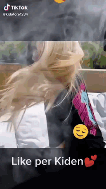 a woman is sitting on a bed with her hair blowing in the wind and says like per kiden