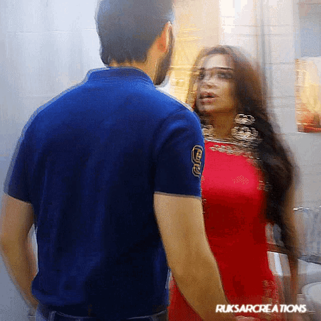 a man in a blue shirt stands next to a woman in a red dress with ruksarcreations written on the bottom right