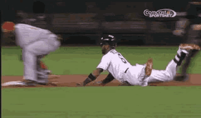 a couple of baseball players are wrestling on a field .