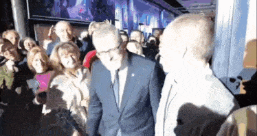a man in a suit and tie is standing in front of a crowd of people