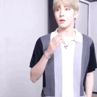 a young man in a striped shirt is standing in a room and looking at the camera .