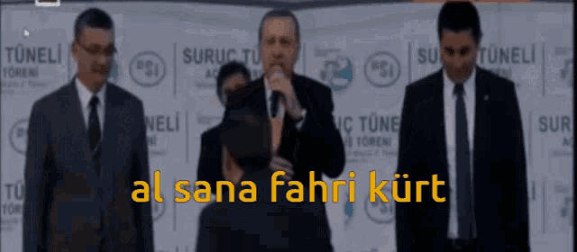 a man speaking into a microphone with the words al sana fahri kurt in yellow