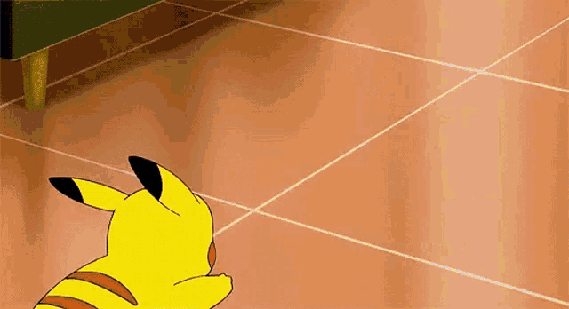 a cartoon pikachu is laying on a tiled floor next to a couch .