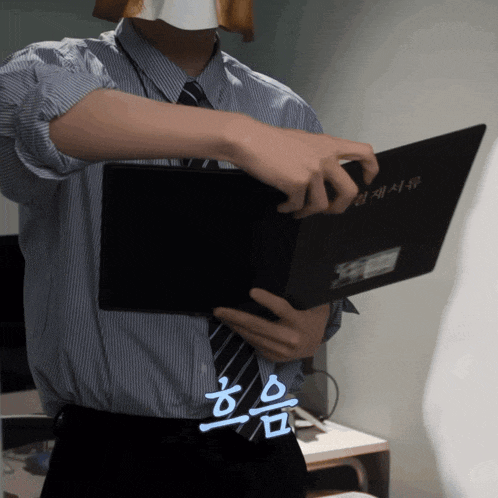 a man in a striped shirt and tie is holding a black book with chinese writing on it