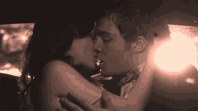 a man and a woman kissing in a car at night