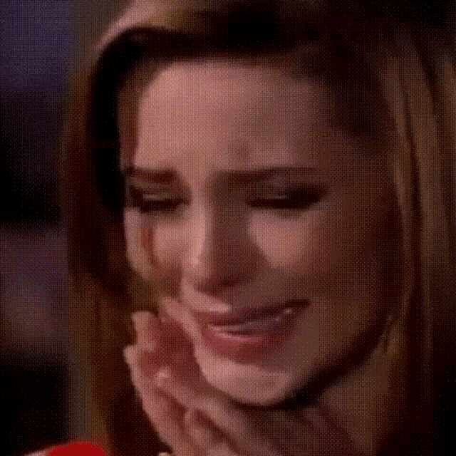 a close up of a woman 's face with her eyes closed and her hands folded .