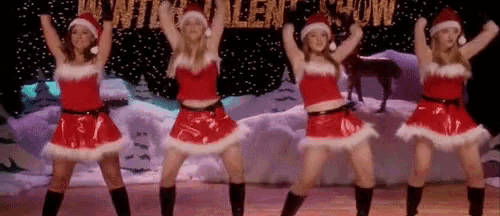 a group of women are dancing in santa claus costumes on a stage .