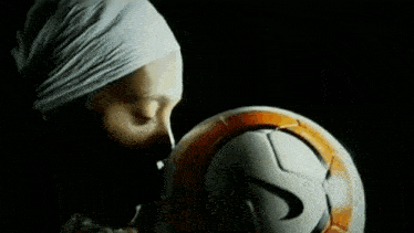 a person with a bandana on their head is looking at a soccer ball