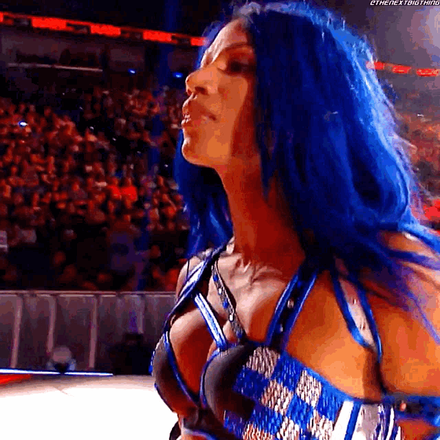 a female wrestler with blue hair is standing in front of a crowd