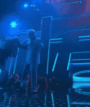 a man in a suit is dancing on stage in front of a crowd