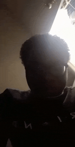 a man with curly hair and glasses is taking a selfie in the dark .