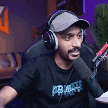 a man is wearing headphones and a hat while talking into a microphone .