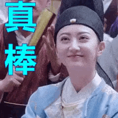 a woman wearing a hat and a blue jacket is sitting in a crowd of people .