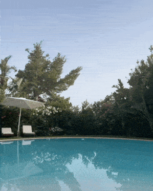 a large swimming pool with a white umbrella and chairs