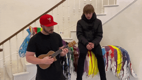 a man playing a guitar next to a boy sitting on a statue of a horse