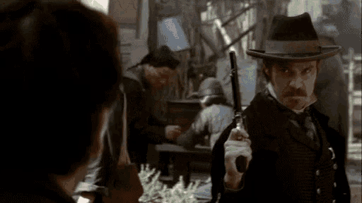 a man in a hat is pointing a gun at someone
