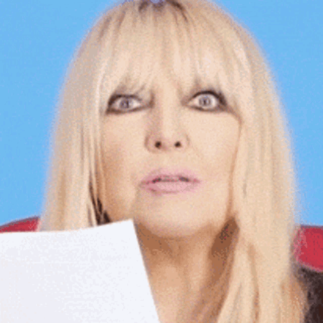 a woman with blonde hair holds a piece of paper in front of her face