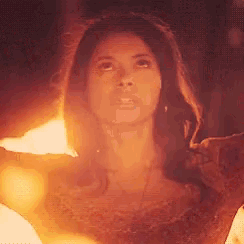 a woman is standing in front of a fire and looking up at it .