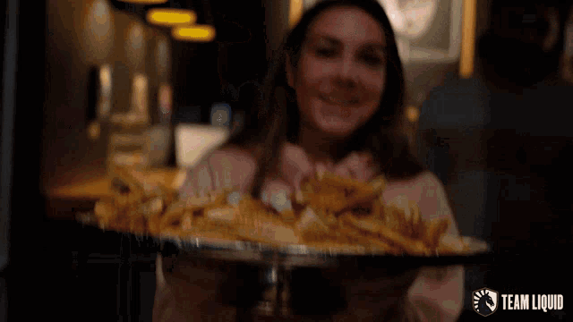 a woman holding a tray of chips with a team liquid logo on the bottom