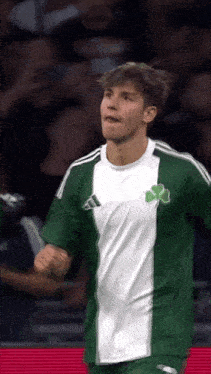 a soccer player wearing a green and white jersey with a clover on it