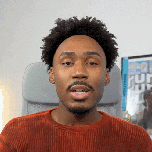 a man in an orange sweater is sitting in a chair