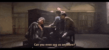 a group of men are sitting around a piano and one of them is asking " can you even see us anymore ? "