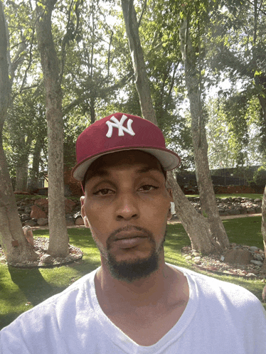 a man wearing a red ny hat and a white shirt