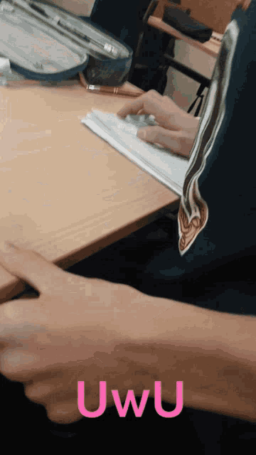 a person sitting at a desk with the word uwu written in pink