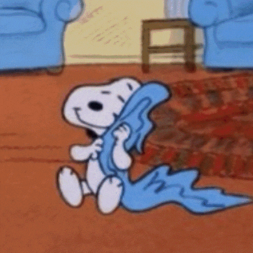 snoopy is sitting on the floor holding a blue blanket in his hands .