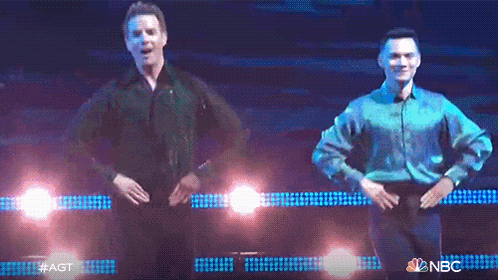 two men are dancing on a stage with a nbc logo in the background