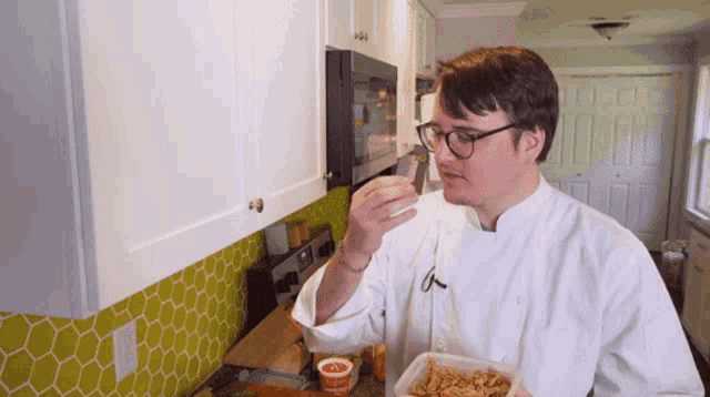 a man in a chef 's uniform is eating a sandwich