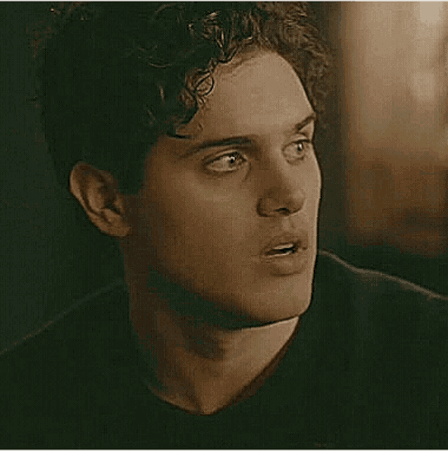 a close up of a young man 's face with a shocked look on his face .