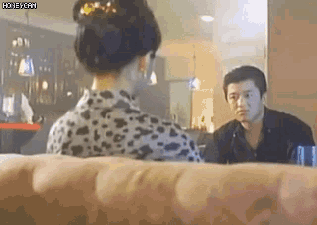 a man and a woman are sitting on a couch talking to each other in a room .