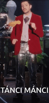 a man in a red jacket and silver pants is standing in front of a sign that says tanti manci