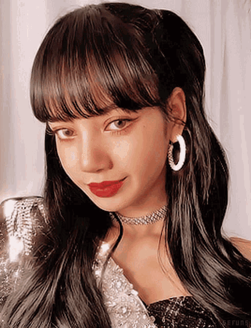 a close up of a woman 's face wearing hoop earrings and a choker
