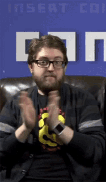 a man clapping in front of a sign that says insert