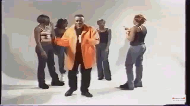a man in an orange jacket is surrounded by women