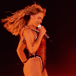 a woman in a swimsuit is singing into a microphone .