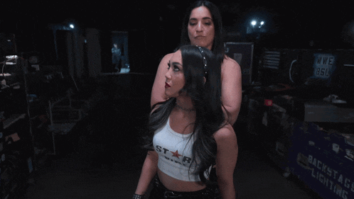 two women standing next to each other with one wearing a white tank top that says star on it