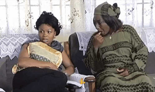 two women are sitting on a couch and talking