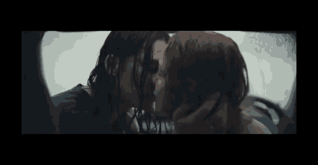 a couple of women kissing in a car in the rain .